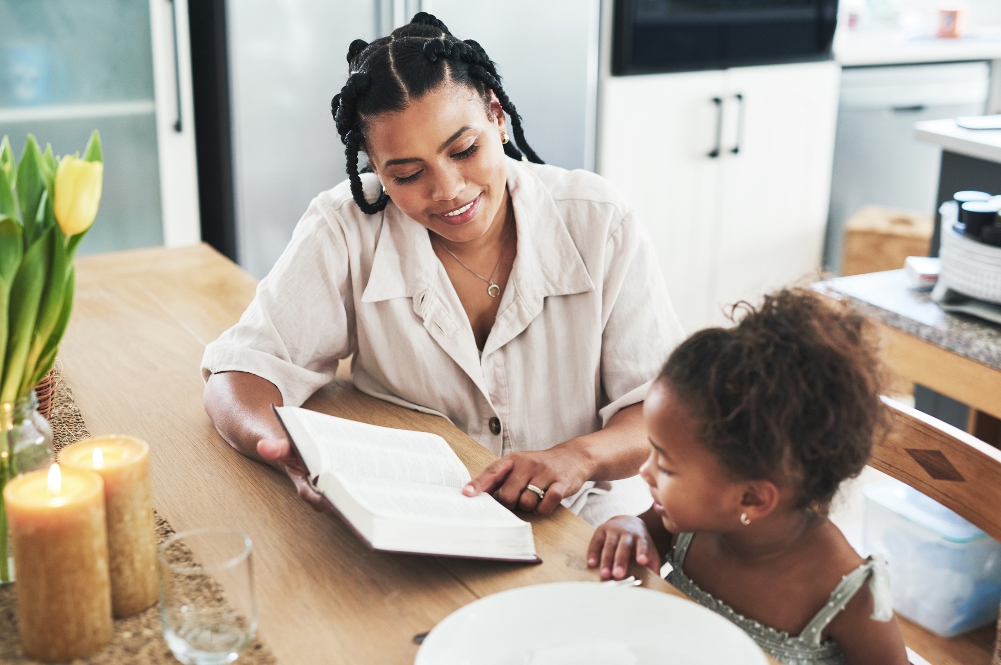 Shot of a mother teaching her daughter about the bible at home